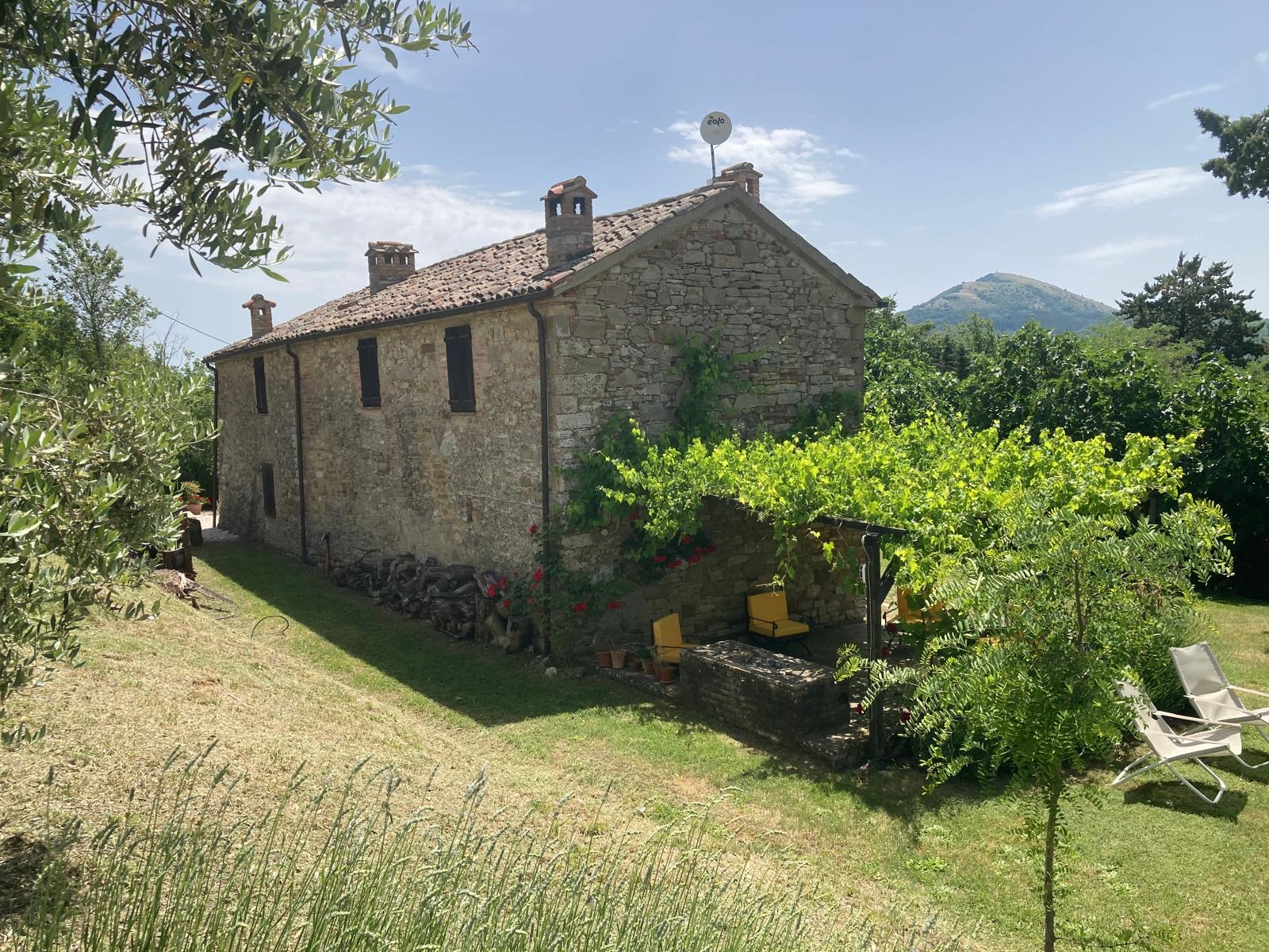 Rear garden at Hilltop Farmhouse with a shaded outdoor seating area, BBQ, comfortable garden furniture and beautiful countryside surroundings.