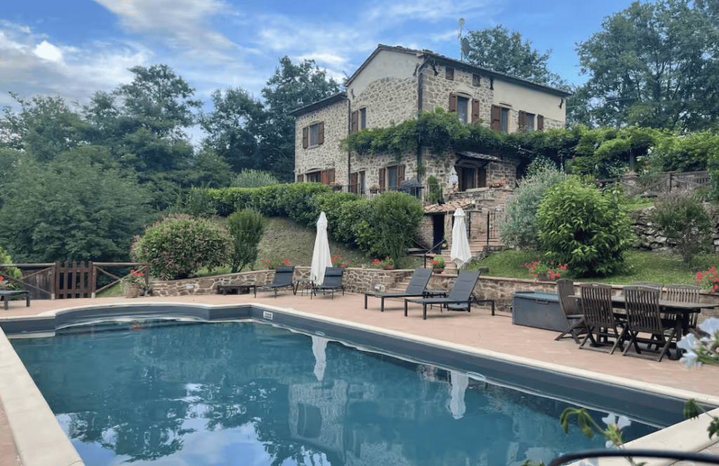 Private secured swimming pool at Villa Tegolaio in Umbria surrounded by countryside and sun loungers, table for eating..