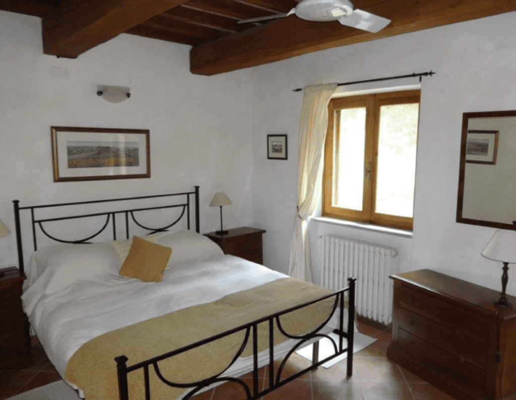 One of four bedrooms at Villa Tegolaio, featuring a double bed and a shared bathroom with the adjacent twin bedroom.