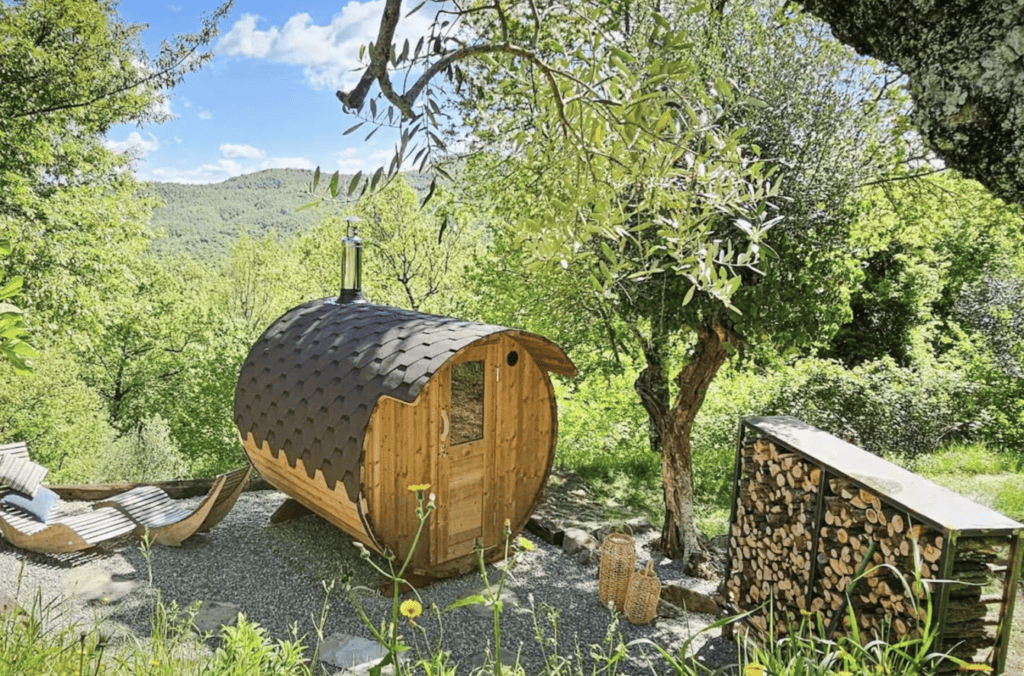 Private outdoor wood-fired sauna at Casa Isabella, surrounded by mature trees and peaceful Umbrian countryside, with relaxation loungers nearby.