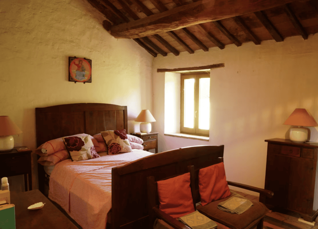 Traditional double bedroom at Hilltop Farmhouse featuring a large original stone fireplace, comfortable furnishings and authentic Umbrian character.